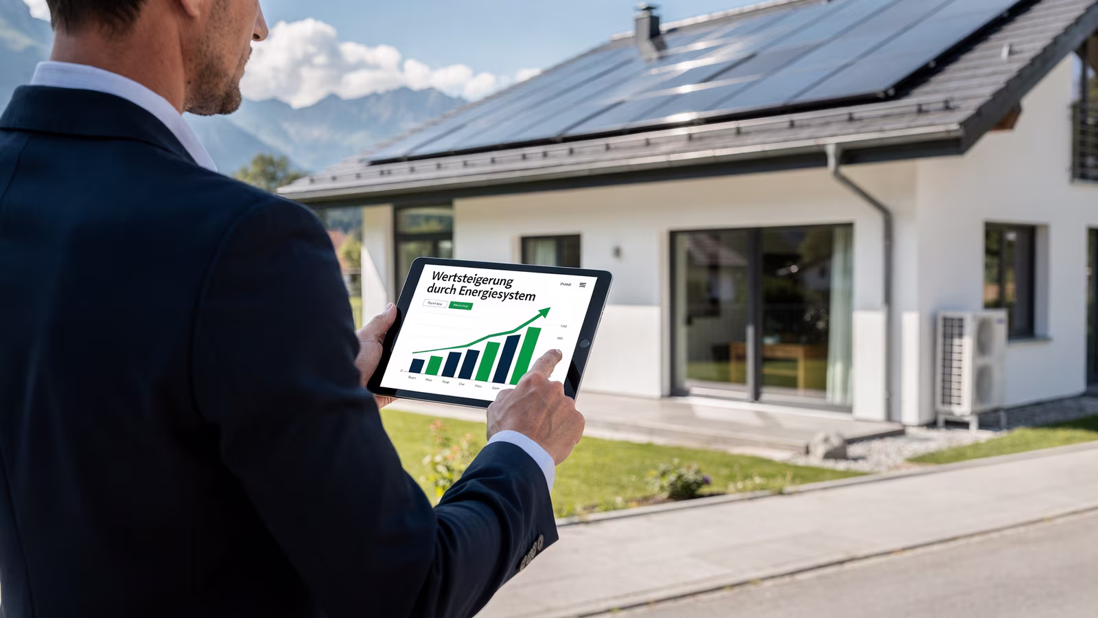 Auswertung des Energiesystems auf einem Tablet vor einem Wohnhaus mit Photovoltaik und Wärmepumpe